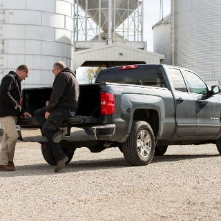 Two men talk on truck tailgate.