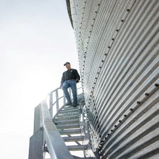 Man walks down grain bin stairs.